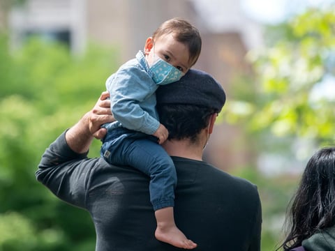 A child sits on his father's shoulder in New York City's Central Park in May 2020. The COVID-19 vaccine isn't presently available to those under 16, raising questions for parents and their kids.
