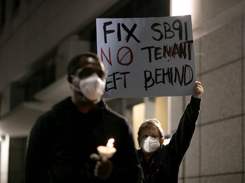 Helen Duffy, back right, a West Oakland landlord holds up a sign decrying SB 91, a rent relief plan signed into law earlier that day by Gov. Gavin Newsom, during a vigil at the Elihu M. Harris, State of California office building in Oakland.
