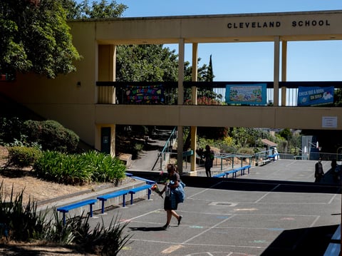 Staff members carrying balloons and bouquets of flowers leave the Cleveland Elementary School campus on the last day of school, May 27, 2021 in Oakland.