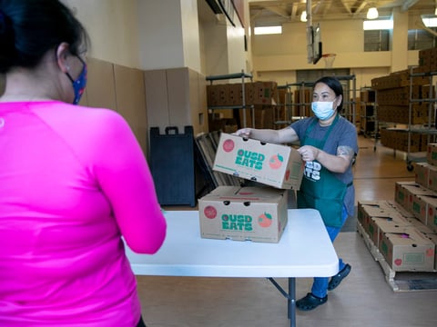 Food service manager Nakheu Saephanh hands out boxes of food to family members at La Escuelita in Oakland on June 7, 2021.