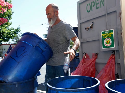 In this photo taken Tuesday, July 5, 2016 James Wilson drops a plastic bottle into a recycling can at a recycling center in Sacramento, Calif.