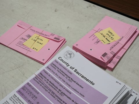 Voters pamphlets and prepaid ballot return envelopes are stacked on a table at the Sacramento County Registrar of Voters office in Sacramento, Calif., Wednesday, Aug. 11, 2021.