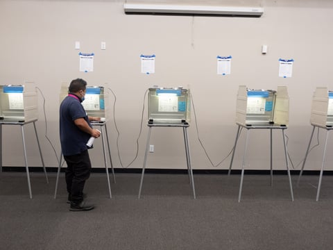 Chan Vang, a bilingual poll worker assisting Hmong speaking voters, sanitizes the polling stations at the Greater Sacramento Urban League on Tuesday, Sept. 14.