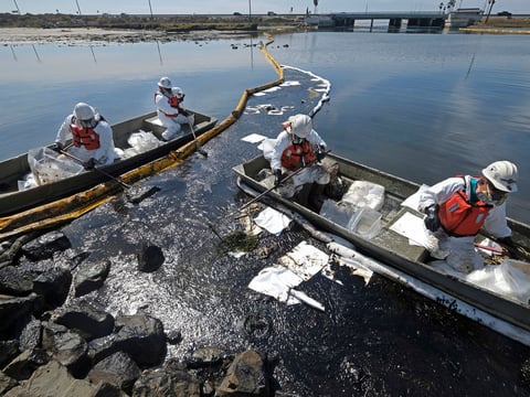 Cleanup contractors deploy skimmers and floating barriers known as booms to try to stop more oil from seeping into the Talbert Marsh in Huntington Beach on Oct. 3, 2021.