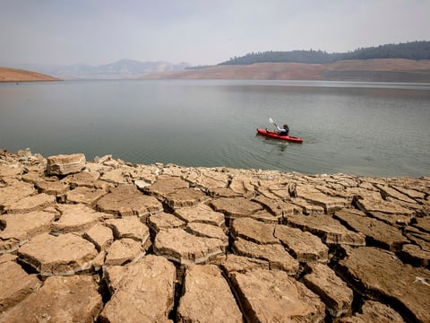 A kayaker fishes in Lake Oroville as water levels remained low due to continuing drought conditions in California on Aug. 22, 2021.