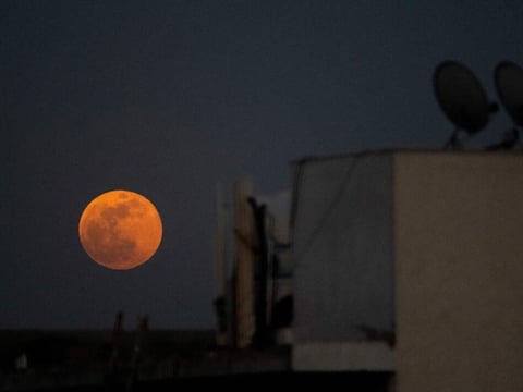 The super blood noon rises over a residential area in New Delhi during a total lunar eclipse in May.