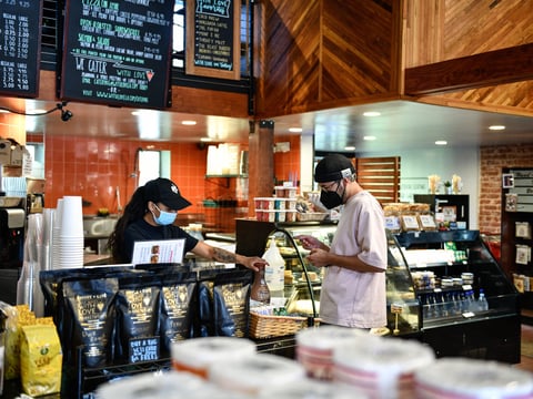Natalie Linares, a barista at With Love Market & Cafe, helps Abraham Rivas-Valle with a transaction in Los Angeles, on August 4, 2021.