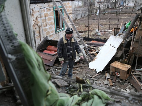A local citizen stands between debris of his house following Ukrainian shelling in the territory controlled by pro-Russian militants, eastern Ukraine, Thursday, Feb. 24, 2022.