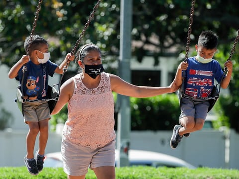 A woman and two children wear masks at a playground in Los Angeles on July 11, 2020.