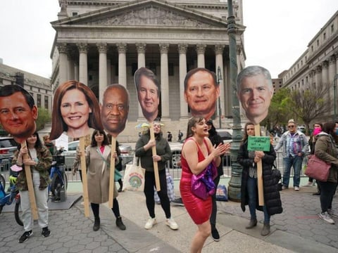 People hold up cardboard cutout of Supreme Court justices as they protest Tuesday in New York in reaction to the leak of the U.S. Supreme Court draft abortion ruling.