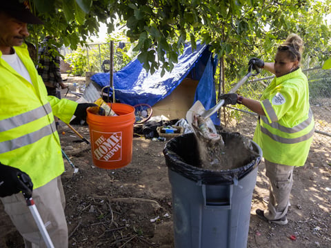 Shawna Barnes, right, and her coworker Walter Mullins of The Clean and Safe Team clean up an area in the River District on Tuesday, April 26, 2022.