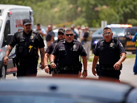 Police walk near Robb Elementary School in Uvalde, Texas, following a shooting Tuesday. A gunman killed 14 children and a teacher, the governor said.