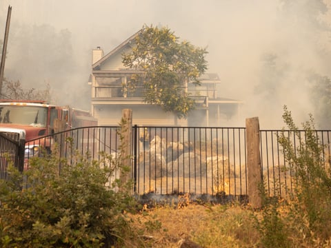 A home is threatened by flames, but is monitored by firefighters on Michigan Bluff Road during the Mosquito Fire, Wednesday, Sept. 7, 2022.
