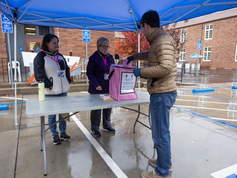 Beth Stern and Christine Giri help with mail-in ballot submission in the rain at the CLARA Center in Sacramento, Calif., on Tuesday, Nov. 8, 2022.