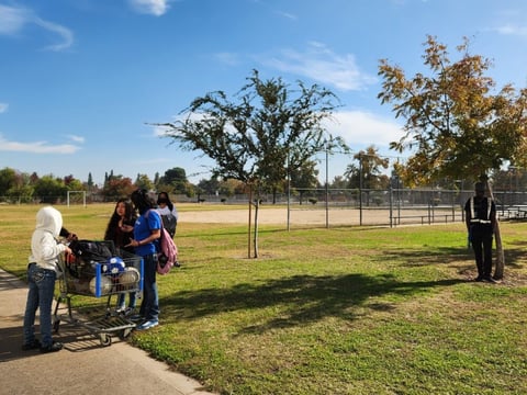 Students and a security guard at Tehipite Middle School stand around some of the trees planted to mitigate pollution.