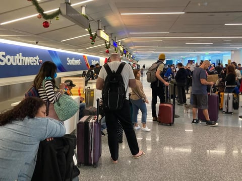 Travelers wait at a Southwest Airlines baggage counter after flight cancellations hit Los Angeles International Airport on Monday. The airline warns it will fly about one-third of its schedule for the next several days.