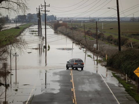 A car stops on a flooded Lambert Road off Interstate 5 in Sacramento County on Jan. 3, 2023. Northern California was hit by a major rainstorm that caused power outages, landslides and flooding over the New Year's holiday weekend.