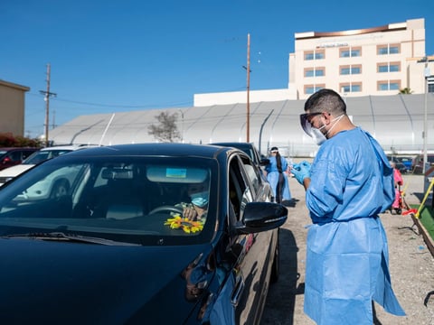 A staff member of Total Testing Solutions checks in a patient who had been waiting two hours at a COVID-19 testing site in Boyle Heights, Los Angeles on Jan. 5, 2022.
