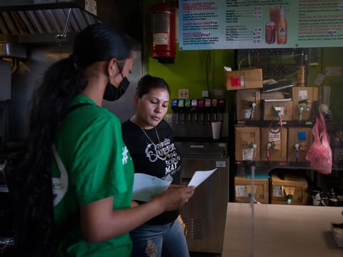 Melissa Lopez explains the covid testing process to a taco shop employee in Fresno, California, as part of her training as a health educator.