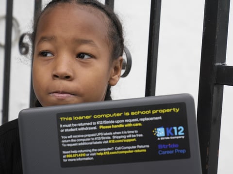 Ezekiel West, 10, opens up his K12/Stride school loaner laptop computer outside his home in Los Angeles on Sunday, Jan. 15, 2023.