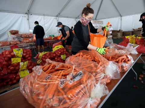 In this April 18, 2020, file photo, San Francisco-Marin Food Bank volunteers pack food into bags to be delivered to people in San Francisco.