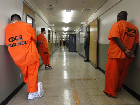 In this Jan. 12, 2012, file photo, inmates wait in the hallway for treatment at the infirmary of the Deuel Vocational Institute near Tracy, Calif.