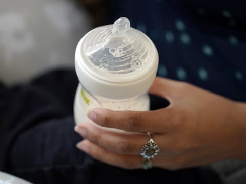A woman holds a bottle of baby formula as she feeds her infant son in San Antonio on May 13, 2022.