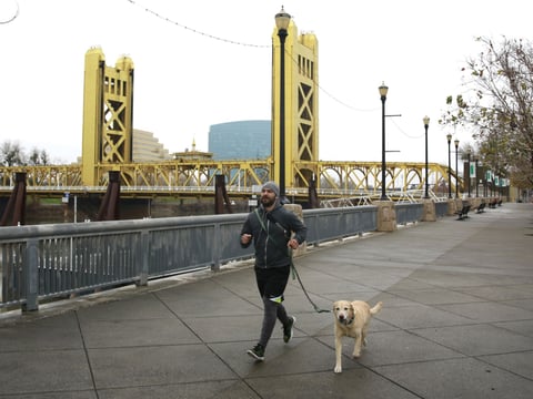 In this Jan. 9, 2018 photo, a man runs with his dog on the river walk along the Sacramento River.