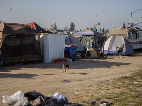 Tents line up against a fence at a homeless encampment near Highway 180 in west Fresno on Feb. 11, 2022.