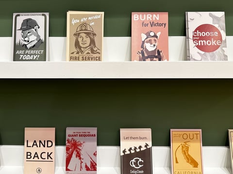 Visitors can pick up postcards showcasing alternate perspectives on wildfires, as well as mascot alternatives to Smokey Bear, at the Pyro Futures exhibition in UC Davis’ Manetti Shrem Museum.