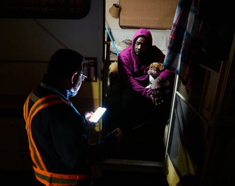 Eric Guerra, a member of the Sacramento city council (l) talks with Charlie Sims and his dog Devo in the doorway of the motorhome they live in during the Point-in-Time (PIT) count of people experiencing homelessness Jan. 24, 2024.