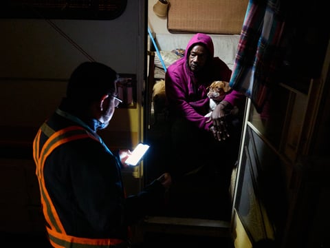 Eric Guerra, a member of the Sacramento City Council, talks with Charlie Sims and his dog Devo in the doorway of the motorhome they live in during the Point-in-Time count of people experiencing homelessness in Sacramento on Jan. 24, 2024.