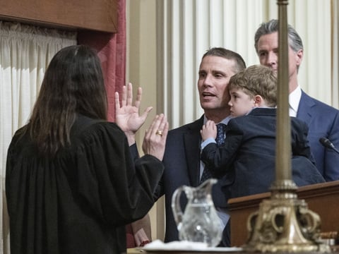 Mike McGuire, D-Healdsburg, holds his son Connor as he is sworn in as Senate President Pro Tempore by California Supreme Court Chief Justice Patricia Guerrero in Sacramento, Calif., Monday, Feb. 5, 2024. California Gov. Gavin Newsom looks on at right