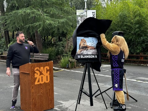 Sacramento Kings MC Scott Freshour unveils the name of the Sacramento Zoo's new lion with the help of Slamson the mascot.