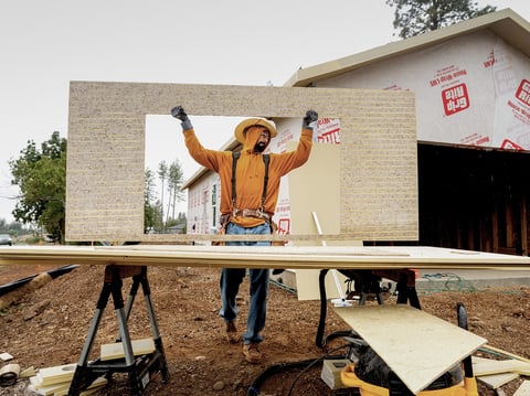 Jose Villanueva carries siding while building a home in Paradise on Oct. 25, 2023. The project is partly funded by ReCoverCA, a state program providing money to rebuild homes in disaster areas.