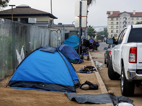 An encampment covers a sidewalk near a freeway entrance in downtown San Diego on March 22, 2024.