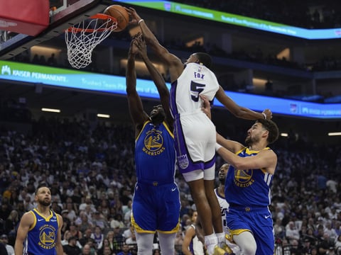 Sacramento Kings guard De'Aaron Fox (5) dunks over Golden State Warriors forward Draymond Green (23) during the first half of an NBA basketball play-in tournament game Tuesday, April 16, 2024, in Sacramento, Calif.