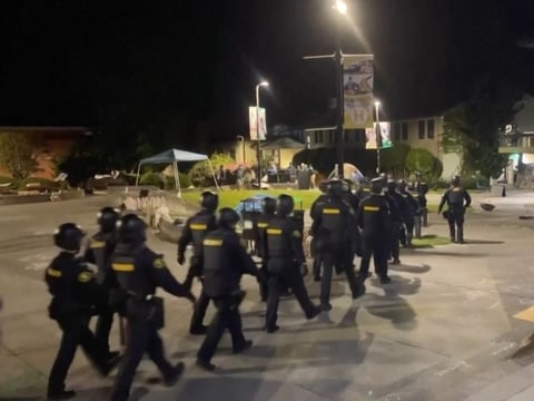 Police with helmets and batons march onto California State Polytechnic University, Humboldt on April 30, 2024 to arrest protesters who had occupied two buildings.