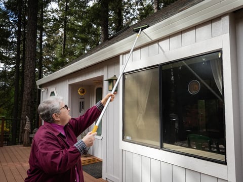 Donna Yutzy cleans the gutters of her home from flammable debris in the Magalia area of Butte County on Nov. 4, 2023. State law prohibits the use of landscaping plants and any flammable materials within a five-foot radius of the house.