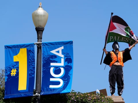 Demonstrators wave flags on the UCLA campus, after nighttime clashes between Pro-Israel and Pro-Palestinian groups, May 1, 2024, in Los Angeles.