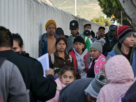Migrants form a line to enter the U.S. and seek asylum through El Chaparral port of entry in San Diego at the Mexico border on Dec. 22, 2022.