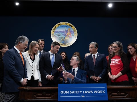 Flanked by lawmakers and gun safety advocates, Gov. Gavin Newsom signs new gun legislation into law in Sacramento on Sept. 26, 2023.