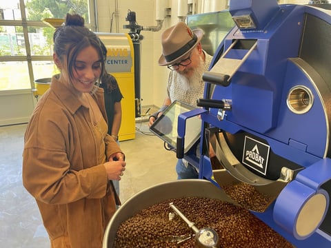 Timothy Styczynski, Head Roaster, UC Davis Coffee Center shows UC Davis Graduating Student Kiara DeGroen, an industrial coffee bean roaster at the Coffee Center at UC Davis in Davis, Calif. on Monday, June 17, 2024. The center which opened last month