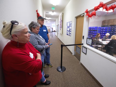From left to right, election observers Susan Wilson, Susanne Baremore, and Tom Morehouse watch through a window as poll workers process ballots at the Shasta County Elections office in Redding, on Nov, 7, 2023.