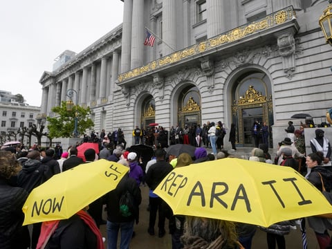 A crowd listens to speakers at a reparations rally outside of City Hall in San Francisco, on March 14, 2023.