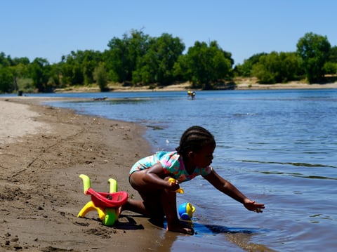 A young girl plays on the sand by the river in Sacramento, Calif., Tuesday, July 2, 2024.