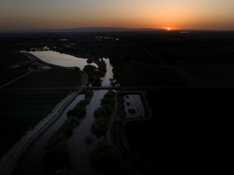 Twilight settles in over the North Fork Kings River in the Island District of Lemoore, Calif., as the sun sets over the horizon on April 19, 2023.