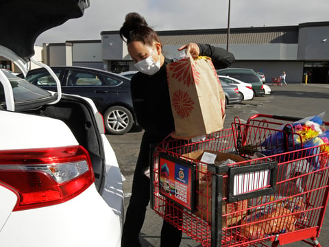 In this July 1, 2020 file photo, Instacart worker Saori Okawa loads groceries into her car for home delivery in San Leandro, Calif.
