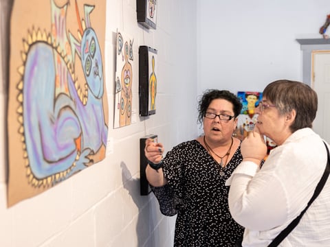 Artist Steff Echeverria speaks with Patricia Wentzel during the reception for her first art show “Love More” held at the Women's Wisdom Art center Sunday, July 7.