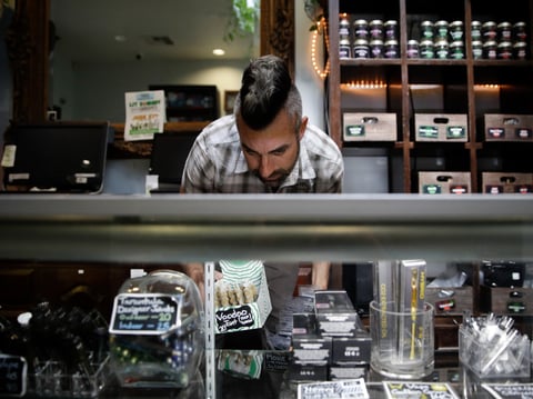 In this June 27, 2017, photo, Jerred Kiloh, owner of the Higher Path medical marijuana dispensary, stocks shelves with with cannabis products in Los Angeles.